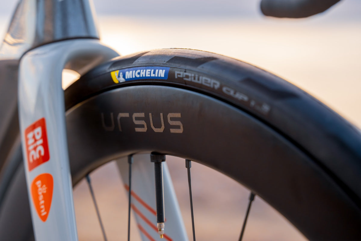 Pneu Michelin Power Cup monté sur une jante carbone Ursus, gros plan sur la fourche avant